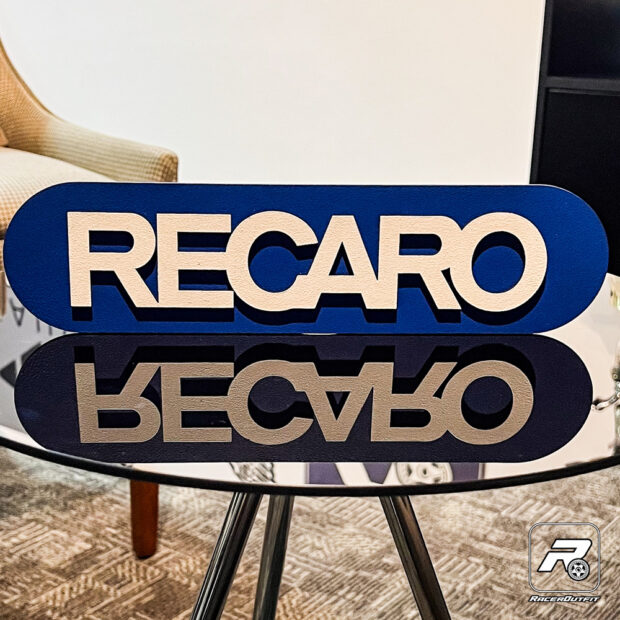 Placa Decorativa Recaro Com uma paleta de cores que evoca elegância e desempenho, esta placa incorpora a qualidade e o prestígio pelos quais a Recaro é reverenciada. Cada traço é pintado à mão com habilidade excepcional, garantindo que esta peça seja uma homenagem digna da marca.